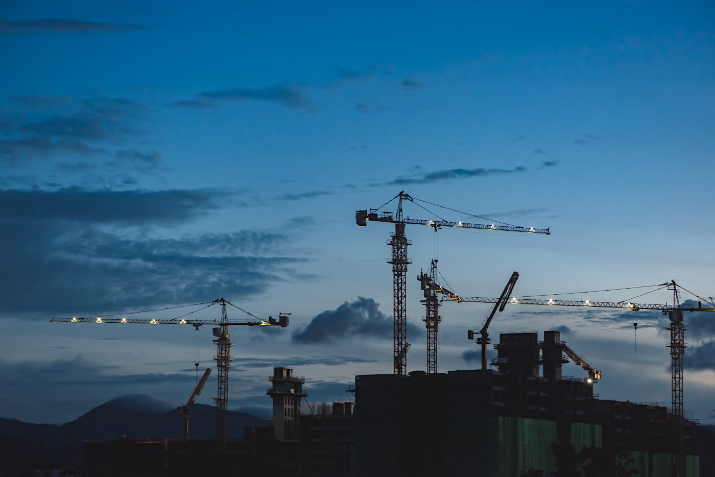Tower cranes at work on construction site during dusk